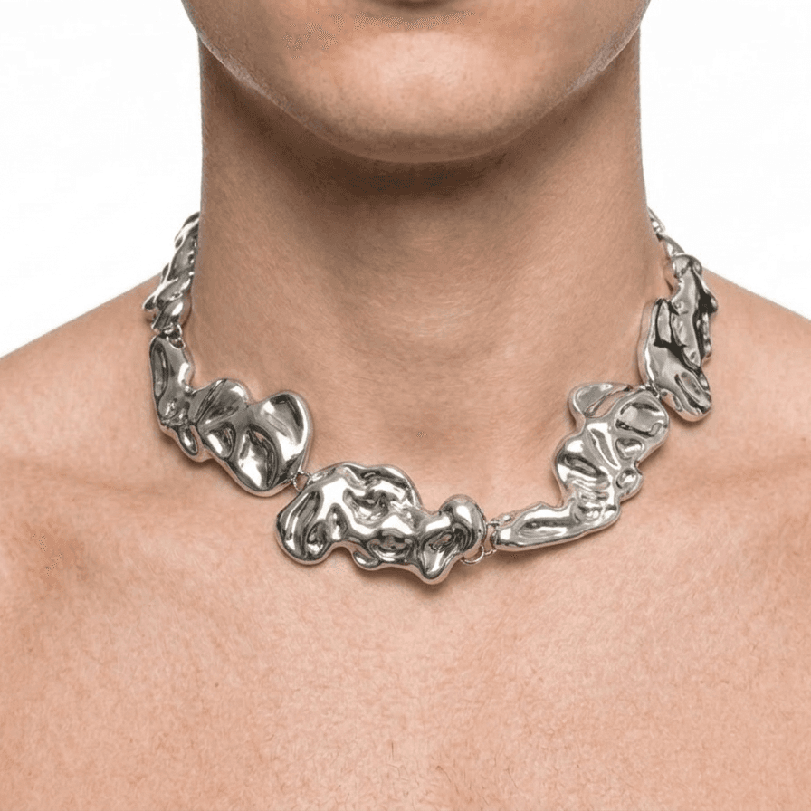 The collar worn at the base of a man's throat, the plates curving along the collarbone, on a white backdrop.